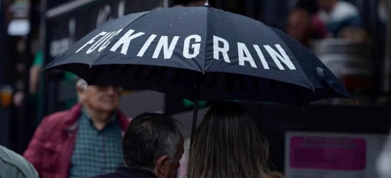 FOTOGRAFÍA. OVIEDO (ASTURIAS) ESPAÑA, 24.10.2022. Una pareja se protege de la lluvia con un paraguas que dice Puta Lluvia, en inglés «fucking Rain», en una calle del centro de Oviedo (Asturias) España. Lluvia, precipitaciones, mal tiempo, agua, rain, fucking Rain, puta lluvia, tormenta. Efe