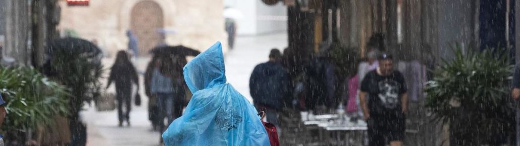 FOTOGRAFÍA. MURCIA (ESPAÑA), 07.02.2023. una mujer se protege de la lluvia con un chubasquero, en la calle Trapería de Murcia. Efe