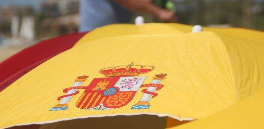 FOTOGRAFÍA. PREMIA DE MAR (BARCELONA) ESPAÑA, 05 DE AGOSTO DE 2023. Cielos poco nubosos o despejados en España. Varios vecinos catalanes participan en una plantada de sombrillas de colores y simbolos institucionales del Reino de España en la playa de Premia de Mar (barcelona), formando la letra «Ñ» y dejando un claro mensaje al nuevo Gobierno de España que previsiblemente necesitará los síes del partido del prófugo d ela Justicia y golpista Carles Puigdemont Casamajò, Juntos por Cataluña (JxCat). Temperaturas. Lasvocesdelpueblo (Ñ Pueblo)