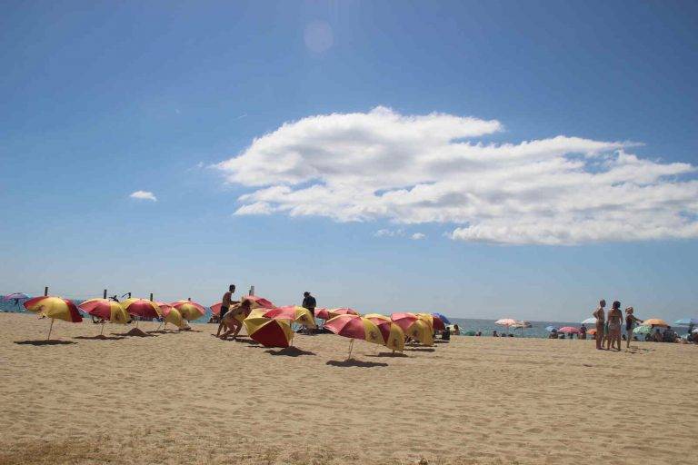 FOTOGRAFÍA. PREMIA DE MAR (BARCELONA) ESPAÑA, 05 DE AGOSTO DE 2023. Varios vecinos catalanes participan en una plantada de sombrillas de colores y simbolos institucionales del Reino de España en la playa de Premia de Mar (barcelona), formando la letra «Ñ» y dejando un claro mensaje al nuevo Gobierno de España que previsiblemente necesitará los síes del partido del prófugo d ela Justicia y golpista Carles Puigdemont Casamajò, Juntos por Cataluña (JxCat). Temperaturas. Lasvocesdelpueblo (Ñ Pueblo)