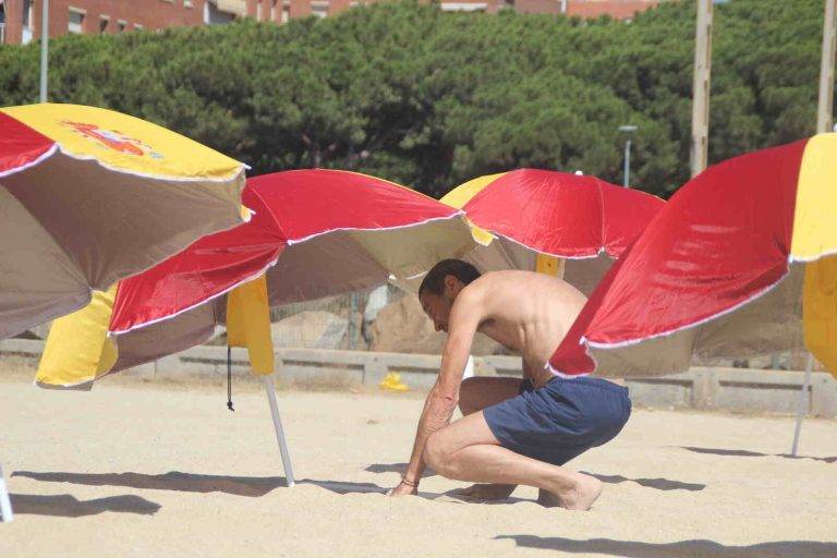 FOTOGRAFÍA. PREMIA DE MAR (BARCELONA) ESPAÑA, 05 DE AGOSTO DE 2023. Varios vecinos catalanes participan en una plantada de sombrillas de colores y simbolos institucionales del Reino de España en la playa de Premia de Mar (barcelona), formando la letra «Ñ» y dejando un claro mensaje al nuevo Gobierno de España que previsiblemente necesitará los síes del partido del prófugo d ela Justicia y golpista Carles Puigdemont Casamajò, Juntos por Cataluña (JxCat). Temperaturas. Lasvocesdelpueblo (Ñ Pueblo)