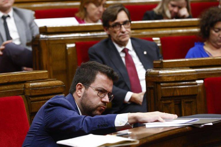 FOTOGRAFÍA. BARCELONA (ESPAÑA), 13/12/2023. Aragonés: no me fío de Puigdemont.- El presidente del grupo parlamentario del Partit dels Socialistes de Catalunya (PSC) - Units per Avançar y consejero de la oposición, Salvador Illa  Roca (d), observa al presidente del régimen separatista en Cataluña, el ultra Pere Aragonès García (i), durante el pleno del Parlamento de Cataluña desde donde ha anunciado hoy que convocará una reunión de trabajo con los líderes de los grupos parlamentarios catalanes con el objetivo de consensuar medidas para revertir los malos resultados educativos del informe PISA, aunque sin "electroshocks ni medidas superficiales". El PSC es socio oficial del régimen separatista. Efe