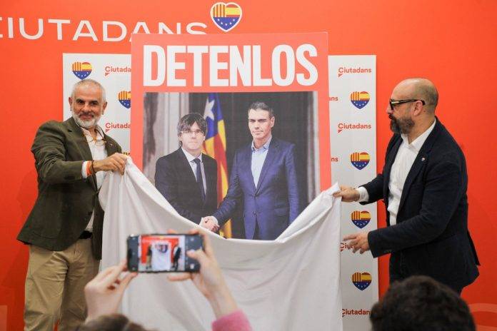 FOTOGRAFÍA. BARCELONA (REINO DE ESPAÑA), 08 DE ABRIL DE 2024. Cs acusa a PIMEC de amigo de "poderes fácticos" separatistas. Cs exige detener a Puigdemont y Sánchez en su cartel del 12M. Cartel electoral Cs "Detenlos" deja ver en él se ve, en primer plano, una "visita de Estado" de un "presidente español, Pedro Sánchez Pérez-Castejón (fondo dcha), a un presidente de una Cataluña independiente, Carles Puigdemont Casamajó (fondo izd), con una bandera separatista, la "estelada", de fondo.; una iniciativa presentada por el eurodiputado, jefe de campaña del 12M y portavoz nacional de este partido, Jordi Cañas Pérez (d), y por el candidato de la formación naranja a la Presidència del Govern de la Generalitat de Catalunya, Carlos Carrizosa Torres (i), este lunes en Barcelona. Lasvocesdelpueblo (Ñ Pueblo)