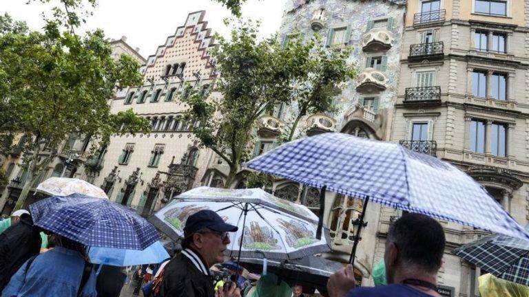 FOTOGRAFÍA. BARCELONA (REINO DE ESPAÑA), 01 DE JULIO DE 2024. Lluvias débiles y dispersas en el Reino de España. Varios turistas se protegen de la lluvia este lunes en las inmediaciones de la Casa Batlló del paseo de Gracia de Barcelona. Efe