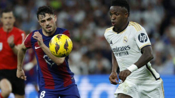 FOTOGRAFÍA. MADRID (REINO DE ESPAÑA), 21 DE ABRIL DE 2024. El clásico se jugará el sábado 26 de octubre a las 21.00 horas en el Bernabéu. El centrocampista del FC Barcelona Pedri (i) lucha con el brasileño Vinicius Jr., del Real Madrid, en el estadio Santiago Bernabéu de Madrid en foto de archivo de Juanjo Martín. Efe