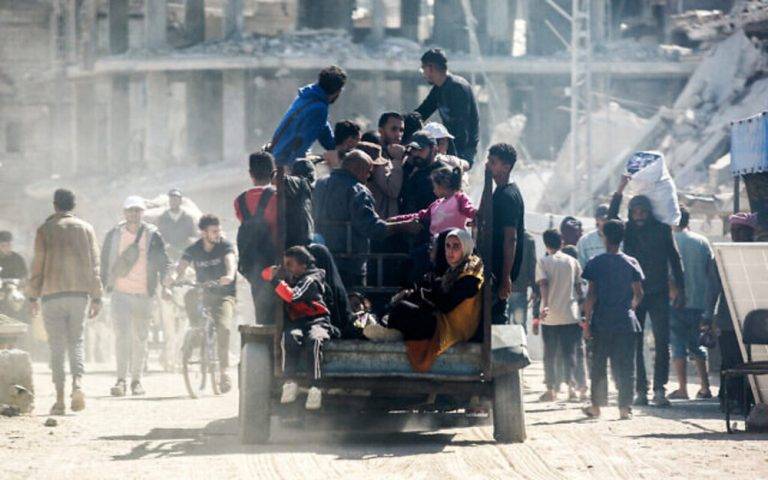 FOTOGRAFÍA. JABALIYA (FRANJA DE GAZA) PALESTINA, 24 DE OCTUBRE DE 2024. La gente viaja en la parte de atrás de un camión que se mueve más allá de los edificios destruidos en la zona de Al-Mawasi de Khan Younis en el sur de la Franja de Gaza, este miércoles 23 de octubre de 2024. Afp