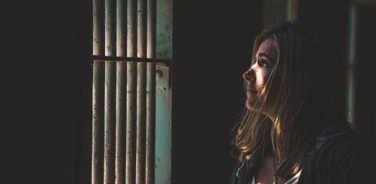FOTOGRAFÍA. SEVILLA (REINO DE ESPAÑA), 22 DE OCTUBRE DE 2024. Detalle de un primer plano de una mujer mirando fuera de una ventana de rejas con el sol brillando en su rostro. Imagen creada por Freepik/Lasvocesdelpueblo (Ñ Pueblo)