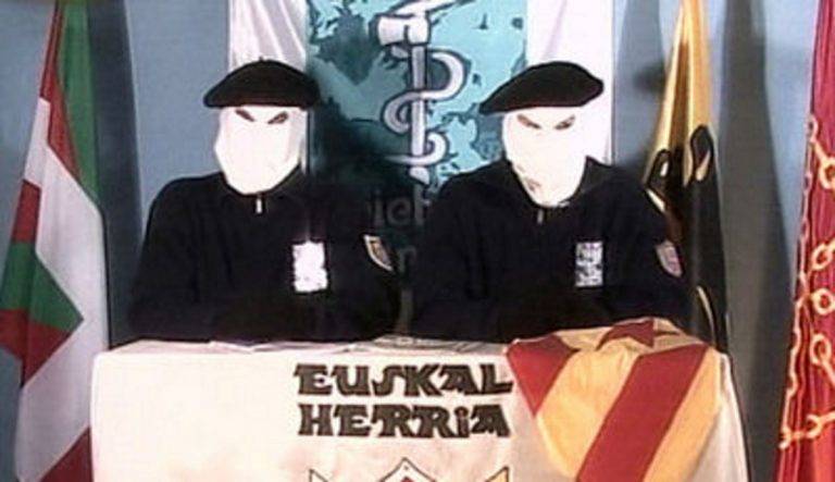 FOTOGRAFÍA. SAN SEBASTIÁN (LAS VASCONGADAS) REINO DE ESPAÑA. 18 DE FEBRERO DE 2004. Con el trapo de la separación de Cataluña del resto del Reino de España "Estrellada" sobre su mesa por primera vez, dos terroristas encapuchados del grupo terrorista comunista separatista "Euskadi Ta Askatasuna (ETA)', expresión en lengua regional de País Vasco, euskera, traducible al español como "País Vasco y Libertad", un organización asesina de tiro a la nuca y coches bomba, aparece durante su habitual lectura de comunicado, donde anuncian que "van a dejar de matar en Cataluña", tras su masacre en Hipercor. El 18 de febrero de 2004 ETA hace público un comunicado en el que anuncia una tregua solo en Cataluña, no en el resto de España. Afirma en el comunicado que lo hace porque Cataluña al igual que el País Vasco es una "nación oprimida" por España y Francia. Los dos asesinos separatistas comunistas etarras encapuchados que aparecen en el vídeo explican también que se ha producido un cambio político. El anuncio se conoce mes y medio después de la reunión del dirigente de la ultraizquierda separatista Esquerra Republicana de Catalunya (ERC), Josep Lluís Carod Rovira, con el sanguinario etarra en Francia, José Antonio Urrutikoetxea Bengoetxea (Miravalles, Vizcaya, 24 de diciembre de 1950), también conocido como "Josu Ternera",​ un terrorista español que perteneció a Euskadi Ta Askatasuna (ETA), y posteriormente fue diputado en el Parlamento Vasco por "Euskal Herritarrok" entre 1998 y 2005. Lasvocesdelpueblo (Ñ Pueblo).