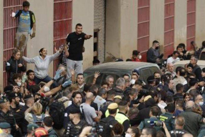 FOTOGRAFÍA. PAIPORTA (VALENCIA) COMUNIDAD VALENCIANA (REINO DE ESPAÑA, 03 DE NOVIEMBRE DE 2024.- El rey Felipe (c) habla vecinos afectados por la riada, durante su visita a Paiporta este domingo. Gritos de 'fuera', así como lanzamiento de barro, están recibiendo a la comitiva de los reyes de España, el presidente del Gobierno, Pedro Sánchez, y el president de la Generalitat, Carlos Mazón, a su llegada al centro de Paiporta. Numerosas personas indignadas han recibido con insultos a la comitiva y se han encarado con ella, mientras que tanto el rey como la reina ha intentado mediar con jóvenes que se les han acercado. Efe