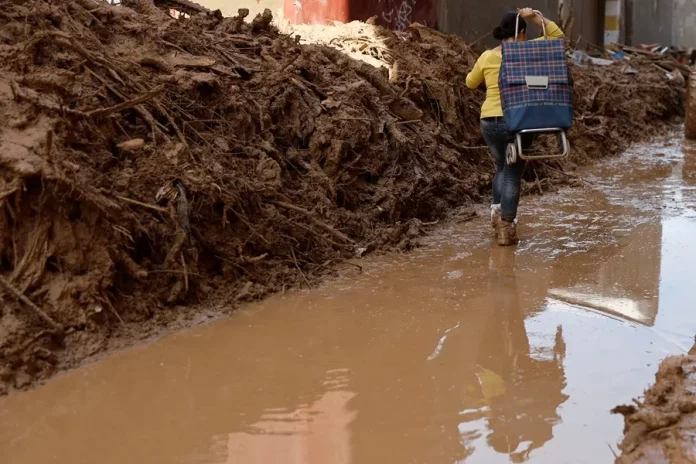 FOTOGRAFÍA. MASANASA (VALENCIA) COMUNIDAD VALENCIANA) REINO DE ESPAÑA, 02 DE NOVIEMBRE DE 2024. Una mujer cruza una calle de la localidad de Masanasa, en Valencia (Comunidad Valenciana). Una mujer cruza una calle de la localidad de Masanasa, en Valencia. La Comunitat Valenciana intenta recuperarse de la peor Depresión Aislada en Niveles Altos (DANA) del siglo en España, que ha dejado más de dos centenares de muertos en esa región, además de un inmenso escenario de daños en carreteras, calles e infraestructuras de numerosas localidades. Una DANA tras fuertes lluvias torrenciales y golpear muy fuertemente al reino de España, con epicentro en la provincia de Valencia (Comunidad Valenciana) donde se ha registrado ya 211 muertos, como cifra provisional para este sábado 2 de noviembre de 20224, y con menos dureza en la provincia de Málaga (Andalucía) y en la región de Castilla-La Mancha. La devastación de los efectos de la DANA que arrasó este martes la provincia de Valencia dejó decenas de personas fallecidas -70 contabilizadas hasta las 16.00 horas-, la angustia de quienes no pueden contactar con sus familiares desde ayer e imágenes desoladoras de la destrucción que han dejado a su paso las inundaciones. En medio de la tragedia, que ha llevado a activar el protocolo de Múltiples Víctimas para identificar a los fallecidos, las autoridades combaten este miércoles un "nuevo enemigo": los bulos que alertan de supuestas evacuaciones, desbordamientos o la caída del 112, que interrumpen la labor de los servicios de emergencias. La ciudadanía de la provincia ha recibido a primera hora de esta mañana de nuevo en sus móviles un mensaje del sistema Es-Alert para evitar cualquier tipo de desplazamiento por las carreteras de la provincia, muchas de cuales permanecen cortadas e impiden todavía acceder a las zonas más afectadas. Efe