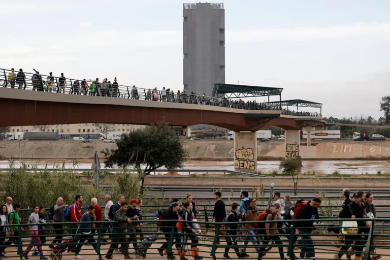FOTOGRAFÍA. LA TORRE (VALENCIA) COMUNIDAD VALENCIANA (REINO DE ESPAÑA), 01 DE NOVIEMBRE DE 2024. Cientos de personas cruzan la pasarela que da acceso al barrio de La Torre, en Valencia, este viernes. La Comunitat Valenciana intenta recuperarse de la peor Depresión Aislada en Niveles Altos (DANA) del siglo en España, que ha dejado más de dos centenares de muertos en esa región, además de un inmenso escenario de daños en carreteras, calles e infraestructuras de numerosas localidades. Una DANA tras fuertes lluvias torrenciales y golpear muy fuertemente al reino de España, con epicentro en la provincia de Valencia (Comunidad Valenciana) donde se ha registrado ya 202 muertos, como cifra provisional para este viernes 1 de noviembre de 20224, y con menos dureza en la provincia de Málaga (Andalucía) y en la región de Castilla-La Mancha. La devastación de los efectos de la DANA que arrasó este martes la provincia de Valencia dejó decenas de personas fallecidas -70 contabilizadas hasta las 16.00 horas-, la angustia de quienes no pueden contactar con sus familiares desde ayer e imágenes desoladoras de la destrucción que han dejado a su paso las inundaciones. En medio de la tragedia, que ha llevado a activar el protocolo de Múltiples Víctimas para identificar a los fallecidos, las autoridades combaten este miércoles un "nuevo enemigo": los bulos que alertan de supuestas evacuaciones, desbordamientos o la caída del 112, que interrumpen la labor de los servicios de emergencias. La ciudadanía de la provincia ha recibido a primera hora de esta mañana de nuevo en sus móviles un mensaje del sistema Es-Alert para evitar cualquier tipo de desplazamiento por las carreteras de la provincia, muchas de cuales permanecen cortadas e impiden todavía acceder a las zonas más afectadas. Efe