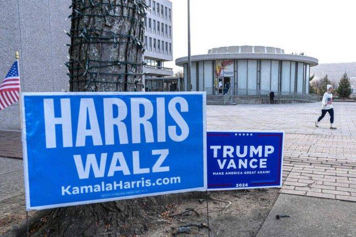 FOTOGRAFÍA. BETHLEHEM (PENSILVANIA) ESTADOS UNIDOS DE AMÉRICA, 05 DE NOVIEMBRE DE 2024. Elecciones Estados unidos 2024 Donald John Trump o Kamala Devi Harris. Una persona camina junto a carteles de los candidatos presidenciales, los demócratas Harris y Walz y los republicanos Trump y Vance, en la entrada de un centro de votación instalado en el gimnasio de la Escuela Secundaria Nitschmann, este martes, en Bethlehem, Pensilvania (Estados Unidos). Efe