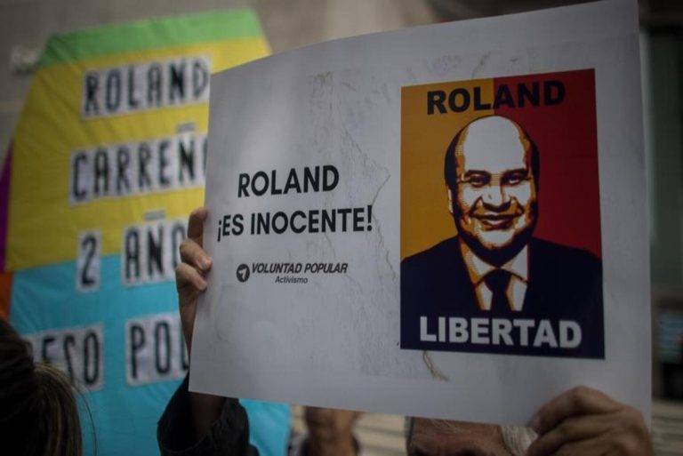 FOTOGRAFÍA. CARACAS (VENEZUELA), 26 DE OCTUBRE DE 2022. Se ha registrado hoy a una persona opositora venezolana que levanta un cartel en apoyo al periodista Roland Oswaldo Carreño Gutiérrez (Roland Carreño), durante una manifestación, en Caracas (Venezuela). El profesional es también político, dirigente del partido opositor venezolano Voluntad Popular (VP), liderado por Leopoldo Eduardo López Mendoza (Leopoldo López). Efe