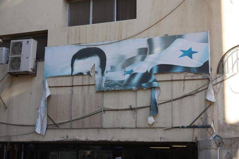 FOTOGRAFÍA. Damascus (Syrian Arab Republic), 08/12/2024.- A torn banner depicting the picture of Bashar al-Assad on a building after rebels took over Damascus, Syria, 08 December 2024. Syrian rebels entered Damascus on 08 December 2024 and announced in a televised statement the 'Liberation of the city of Damascus and the overthrow of Bashar al-Assad,' as well as the release of all the prisoners. The rebels also urged the Syrian armed forces to leave Syrian public institutions, which will stay under the control of the outgoing Syrian prime minister until the official handover ceremony (Siria, Damasco). Efe
