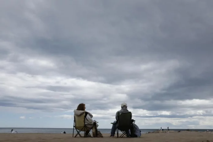 FOTOGRAFÍA. VALENCIA (COMUNIDAD VALENCIANA) REINO DE ESPAÑA, 19 DE ABRIL DE 2025. Una pareja conversa este sábado en una playa de Valencia. El frente frío que ha entrado por Galicia trae un final de Semana Santa marcado por la inestabilidad meteorológica, con fuerte viento, precipitaciones en el centro y mitad oriental peninsular, que podrían ir acompañadas de tormentas, y granizo en zonas del nordeste. Efe