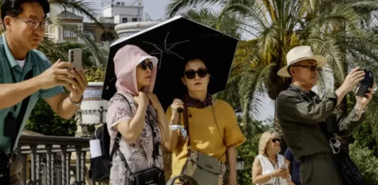 FOTOGRAFÍA. SEVILLA (REINO DE ESPAÑA), 30 DE MAYO DE 2025. Turistas pasean protegidos con paraguas y pañuelos en la plaza de América de Sevilla, este viernes con temperaturas extremas de hasta 40 grados en Andalucía inusual para el último fin de semana de mayo. Efe