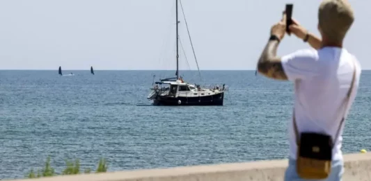 FOTOGRAFÍA. VALENCIA (COMUNIDAD VALENCIANA) REINO DE ESPAÑA, 23 DE JUNIO DE 2025. Un hombre saca una foto junto a un velero en la playa de la Malvarrosa en Valencia este lunes. Efe