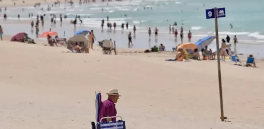 FOTOGRAFÍA. CÁDIZ (ANDALUCÍA) REINO DE ESPAÑA, 31 DE MAYO DE 2025. Un hombre cargado con sillas y sombrillas camina por la playa de Chiclana de la Frontera (Cádiz). Efe