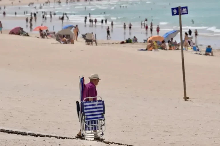 FOTOGRAFÍA. CÁDIZ (ANDALUCÍA) REINO DE ESPAÑA, 31 DE MAYO DE 2025. Un hombre cargado con sillas y sombrillas camina por la playa de Chiclana de la Frontera (Cádiz). Efe