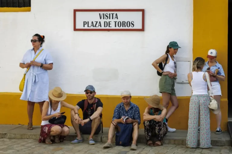FOTOGRAFÍA. SEVILLA (COMUNIDAD AUTÓNOMA DE ADALUCÍA) REINO DE ESPAÑA, 07 DE JUNIO DE 2025. Unos turistas descansaban este sábado a la sombra en la entrada de la Plaza de Toros de la Maestranza de Sevilla. Efe