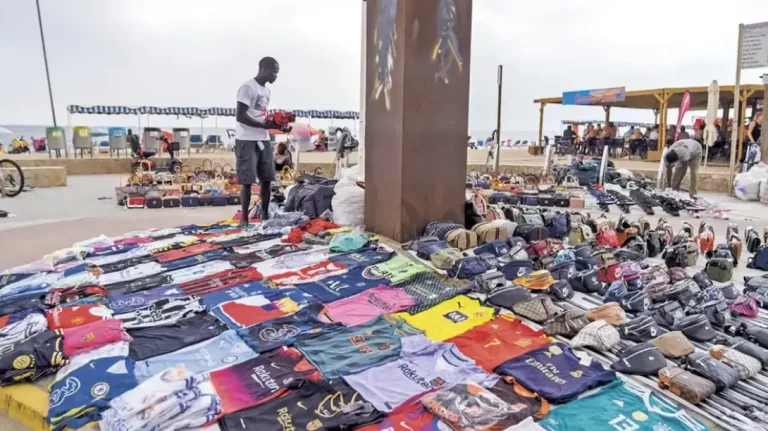 FOTOGRAFÍA. PASEO MIRAMAR (SALOU Y CAMBRILS) TARRAGONA (CATALUÑA) REINO DE ESPAÑA, 23 DE JUNIO DE 2025. Detalle de varios inmigrantes haciendo la venta ilegal ambulante de mercancías falsas o presuntamente robada, conocida como Top Manta en el Paseo Miramar, que conecta las ciudades de la Costa Dorada, Salou y Cambrils (Tarragona), en la Comunidad Autónoma de Cataluña (Reino de España). Lasvocesdelpueblo (Ñ Pueblo)
