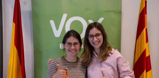 FOTOGRAFÍA. BARCELOAN (CATALUÑA) REINO DE ESPAÑA, 03 DE ABRIL DE 2025. la diputada por Barcelona al Parlamento de Cataluña y portavoz nacional de Juventudes de VOX, Julia Calvet Puig (i), junto a una simpatizante de su formación esta tarde en la sede del partido en calle del Camp 28 de Barcelona, luciendo y exhibiendo la llamada "Pulsera Prohibida" por parte del Partido Socialista (PSOE), mediante una denuncia ante Anticorrupción alegando que los de Santiago Abascal Conde no pueden vender o recibir donaciones de un euro o 50 céntimos de euro o más de sus propios simpatizantes o militantes a cambio de una pulsera o resto de "merchandising" (promoción comercial), en marco de una campaña antiVOX con la que el Gobierno socialista de Pedro Sánchez Pérez-Castejón y el PSOE pretenden frenar el avance imparable de VOX en las instituciones. VOX Barcelona/Lasvocesdelpueblo (Ñ Pueblo)