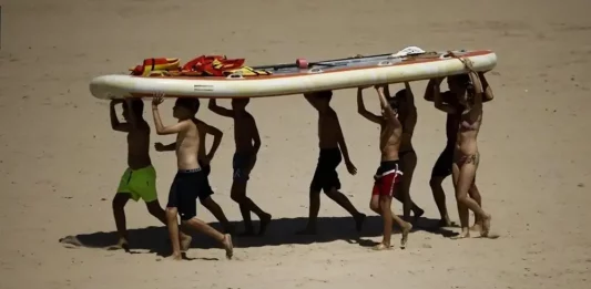 FOTOGRAFÍA. VALENCIA (COMUNIDAD VALENCIANA) REINO DE ESPAÑA, 16 DE JULIO DE 2025. Varias personas transportan una tabla en la playa de la Malvarrosa, Valencia, en la Comunidad Valenciana (Reino de España. Efe