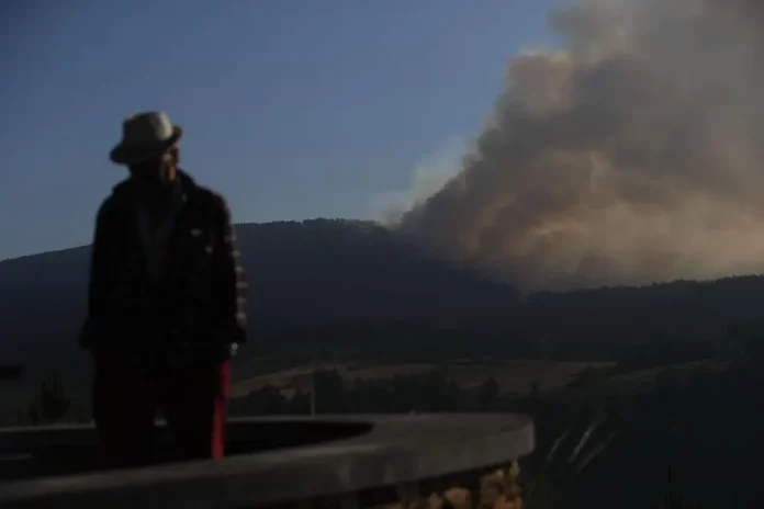 La situación en Orense mejora,incendios España, incendios,Orense,Galicia (3) FOTOGRAFÍA. LUGO (GALICIA) REINO DE ESPAÑA, 26 DE AGOSTO DE 2025. Un hombre camina con la columna de humo de fondo desde el Mirador da Capela en Pobra de Brollón, Lugo. Efe