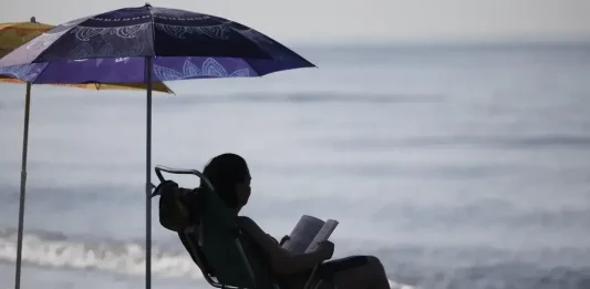 FOTOGRAFÍA. MÁLAGA (ANDALUCÍA) REINO DE ESPAÑA, 13 DE AGOSTO DE 2025. Una mujer lee bajo la sombra de una sombrilla en la playa del Rincón de la Victoria (Málaga), este miércoles. Efe