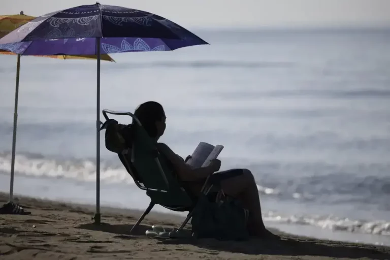 FOTOGRAFÍA. MÁLAGA (ANDALUCÍA) REINO DE ESPAÑA, 13 DE AGOSTO DE 2025. Una mujer lee bajo la sombra de una sombrilla en la playa del Rincón de la Victoria (Málaga), este miércoles. Efe