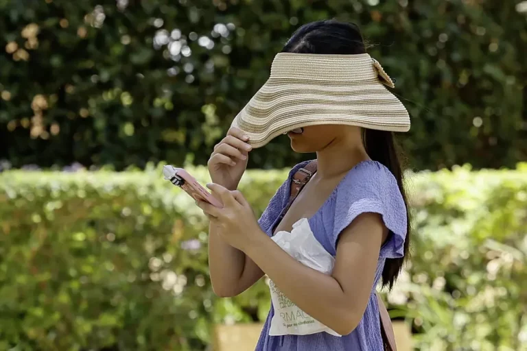 FOTOGRAFÍA. SEVILLA (ANDALUCÍA) REINO DE ESPAÑA, 11 DE AGOSTO DE 2025. Una mujer se tapa con un sombrero la cara para resguardarse del sol mientras camina por un parque en Sevilla en una imagen de archivo. Efe