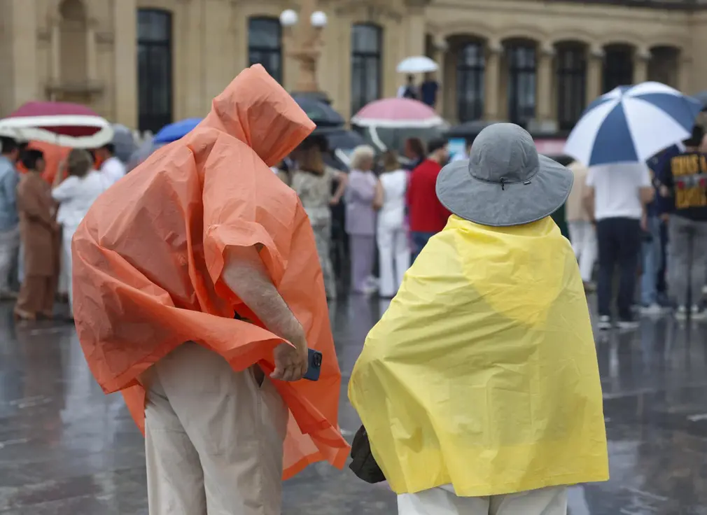 FOTOGRAFÍA. SAN SEBASTIÁN (LAS VASCONGADAS) REINO DE ESPAÑA, 02 DE JULIO DE 2025. Imagen de unos turistas protegiéndose de la lluvia con chubasqueros en julio en San Sebastián. Efe