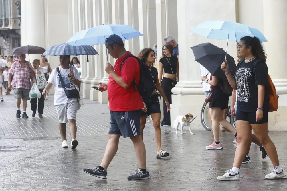 FOTOGRAFÍA. REINO DE ESPAÑA, 19 DE AGOSTO DE 2025. Varias personas se protegen de la lluvia. Efe