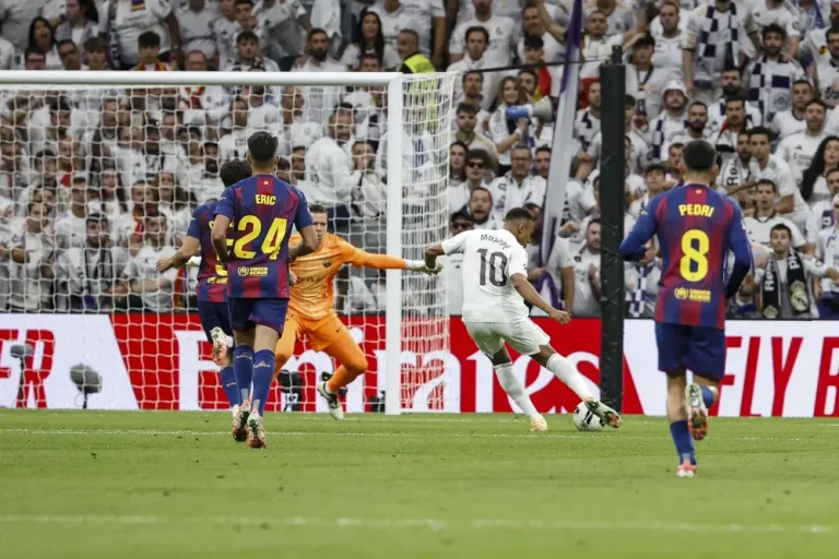FOTOGRAFÍA. MADRID (REINO DE ESPAÑA), 26 DE OCTUBRE DE 2025. El delantero francés del Real Madrid Kylian Mbappé (2d) remata para marcar gol ante el portero del FC Barcelona Wojciech Szczesny, durante el partido de la décima jornada de LaLiga EA Sports, que Real Madrid y FC Barcelona disputan en el estadio Santiago Bernabéu. Efe