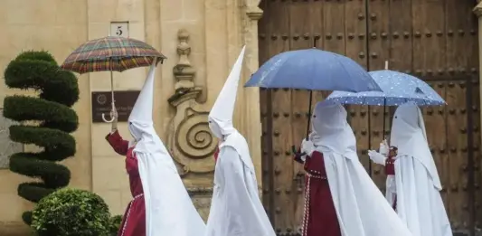 FOTOGRAFÍA. CÓRDOBA (ANDALUCÍA) REINO DE ESPAÑA, 25 DE MARZO DE 2024. Martes Santo de chubascos y lluvias en toda España. Semana Santa. Unos nazarenos de la Hermandad de La Sentencia se protegen de la lluvia con paraguas mientras caminan hacia su templo este lunes en Córdoba. Efe