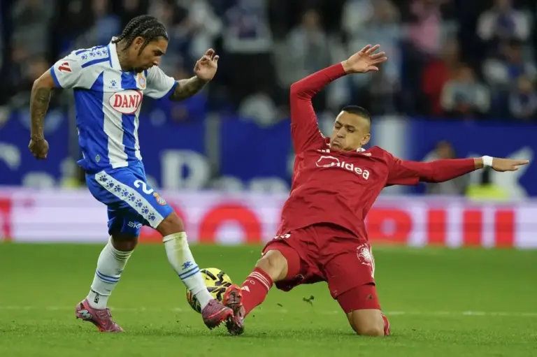 FOTOGRAFÍA. CORNELLÁ DE LLOBREGAT (BARCELONA) CATALUÑA (REINO DE ESPAÑA), 24 DE NOVIEMBRE DE 2025. El centrocampista británico del Espanyol Tyrhys Dolan (i) pelea un balón con el chileno Alexis Sánchez, del Sevilla, durante el partido de la jornada 13 de LaLiga EA Sports entre el RCD Espanyol y el Sevilla FC, este lunes en el RCDE Stadium. Efe