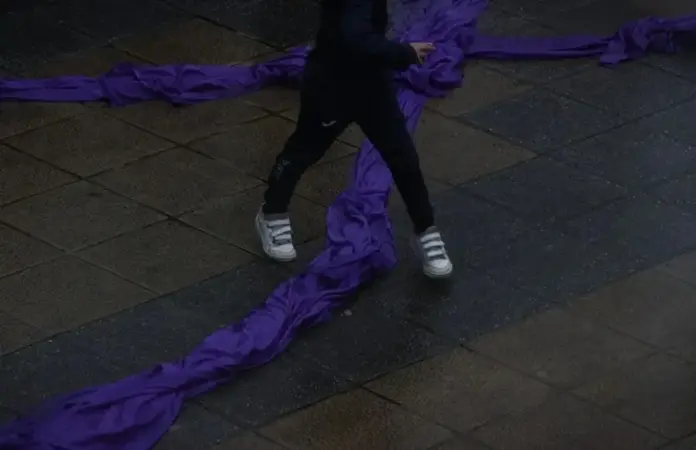 FOTOGRAFÍA. MADRID (REINO DE ESPAÑA), AÑO 2025. Un niño pasa por encima de un gran lazo violeta en la concentración contra la violencia machista. Efe