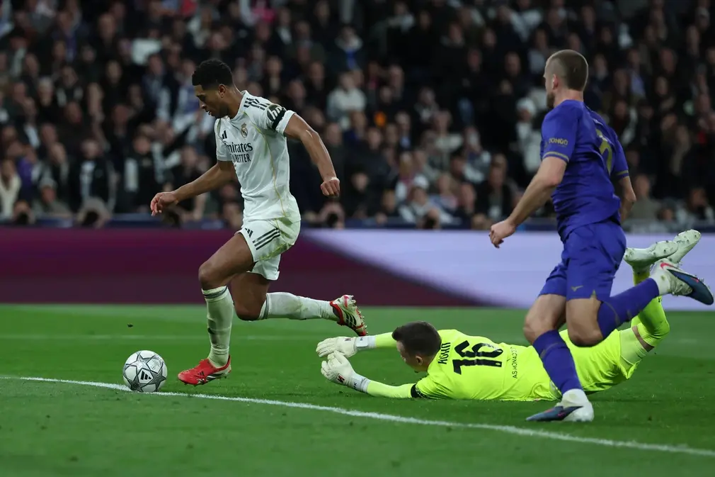 FOTOGRAFÍA. MADRID (ESPAÑA), 20 DE ENERO DE 2026. El centrocampista inglés del Real Madrid, Jude Bellingham (i), supera al guardameta alemán del AS Mónaco, Philipp Köhn, para conseguir el sexto gol del equipo madridista durante el encuentro correspondiente a la Liga de Campeones UEFA que disputaron el Real Madrid y el AS Mónaco, en el estadio Santiago Bernabéu en Madrid. Efe
