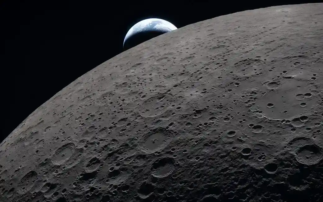 FOTOGRAFÍA. ESPACIO (MÁS ALLÁ DE LA ATMÓSFERA TERRESTRE), 06 DE ABRIL DE 2026. Imágenes capturadas por Artemis II revelan lo nunca antes visto por humanos. La superficie lunar llena el encuadre con gran nitidez, como se observa durante el sobrevuelo lunar de Artemis II, mientras que la Tierra se oculta a lo lejos en el fondo. Esta imagen fue capturada a las 18:41 EDT del 6 de abril de 2026, apenas tres minutos antes de que la nave espacial Orion y su tripulación se ocultaran tras la Luna y perdieran contacto con la Tierra durante 40 minutos antes de emerger al otro lado. En esta imagen, la parte oscura de la Tierra está experimentando la noche, mientras que en su lado diurno se aprecian nubes arremolinadas sobre la región de Australia y Oceanía. En primer plano, el cráter Ohm muestra bordes escalonados y un suelo relativamente plano marcado por picos centrales, formados cuando la superficie rebotó hacia arriba durante el impacto que creó el cráter. Nasa/Lasvocesdelpueblo (Ñ Pueblo)