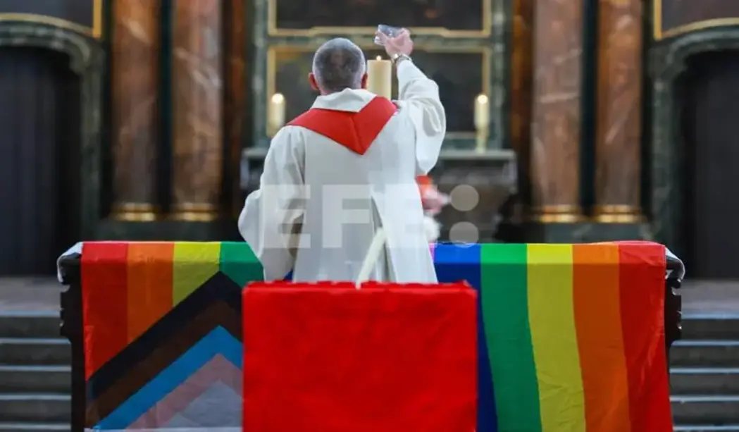 FOTOGRAFÍA. BERLIN (GERMANY), 26 OF JULY OF 2026. Alemania, abatido el islamista Abdul Ballout autor de la masacre de LGTBI. A priest lights a candle placed on a rainbow flag at the altar during a memorial service at St. Mary's Church following a car-ramming attack near the Christopher Street Day (CSD) parade route in Berlin, Germany, 26 July 2026. German Interior Minister Alexander Dobrindt said the 25 July vehicle ramming, which killed one person and injured 29 others, is being investigated as a terrorist attack. Efe