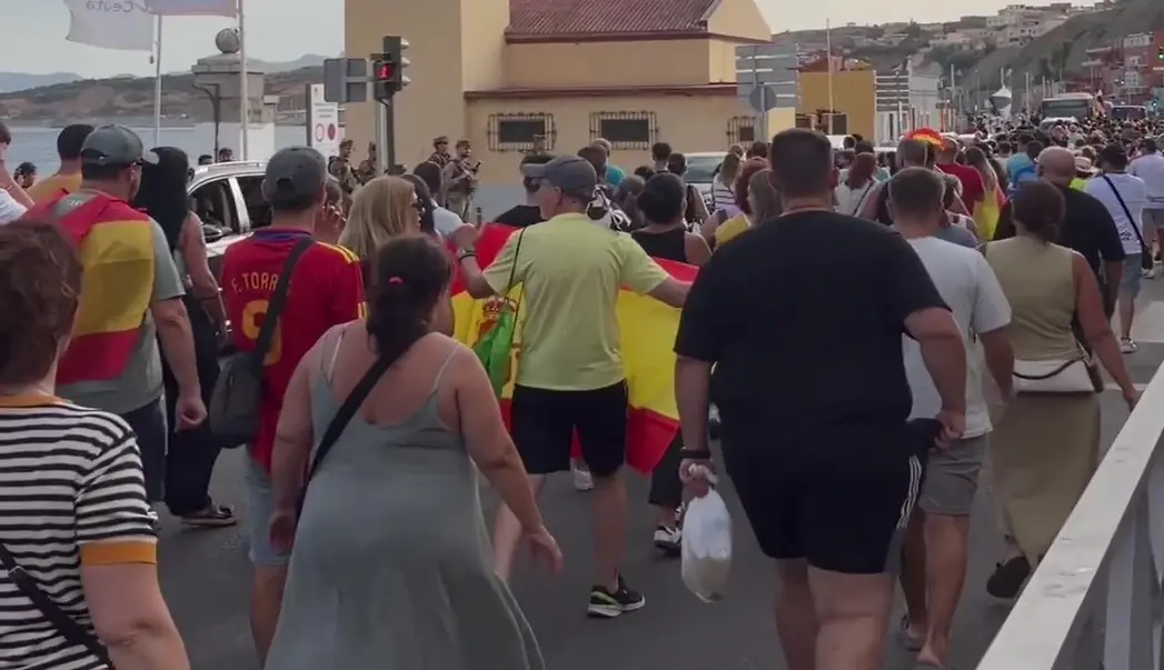 FOTOGRAFÍA. CEUTA (ESPAÑA), 25 DE AGOSTO DE 2026. Ceuta protesta contra acogida de inmigrantes: invasores deportación; invasores expulsión. Varios cientos de vecinos de Ceuta han trasladado este martes hasta la plaza de los Reyes, frente a la Delegación del Gobierno, la protesta contra el posible alojamiento de inmigrantes ilegales -"invasores", apuntan los manifestantes visiblemente hartos y muy desamparados ante la inacción completa de las autoridades locales y nacionales- en distintos puntos de la ciudad, después de que una concentración iniciada en la zona del Fischer se haya convertido en una movilización ciudadana. Lasvocesdelpueblo (Ñ Pueblo)