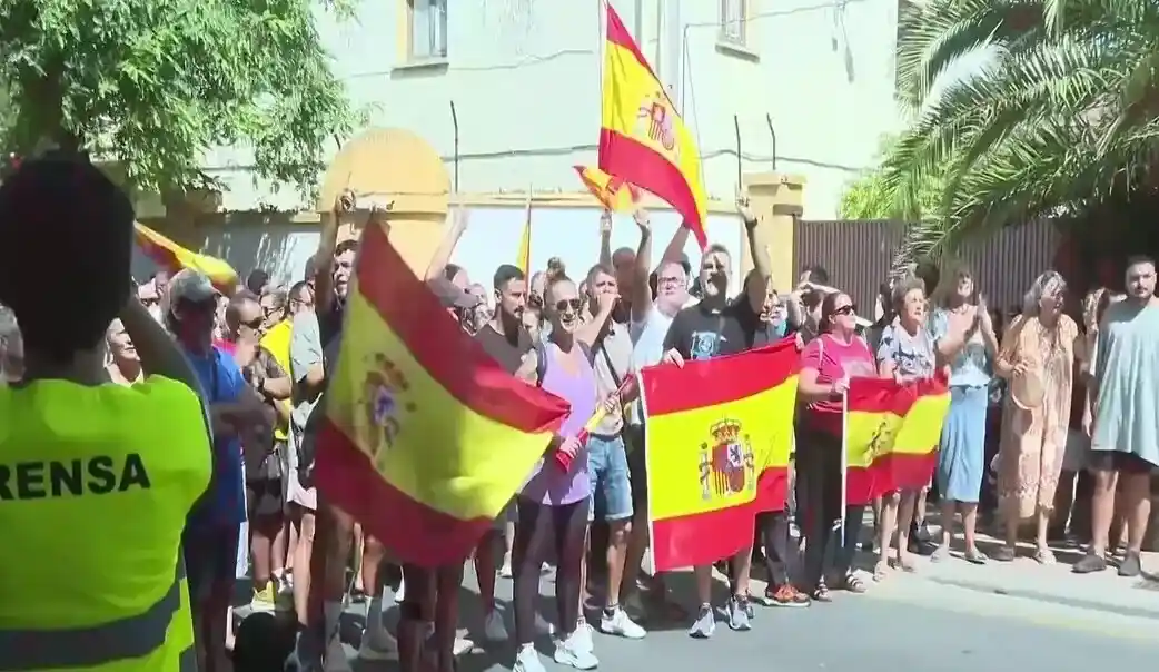 FOTOGRAFÍA. CEUTA (ESPAÑA), 25 DE AGOSTO DE 2026. Ceuta protesta contra acogida de inmigrantes: invasores deportación; invasores expulsión. Varios cientos de vecinos de Ceuta han trasladado este martes hasta la plaza de los Reyes, frente a la Delegación del Gobierno, la protesta contra el posible alojamiento de inmigrantes ilegales -"invasores", apuntan los manifestantes visiblemente hartos y muy desamparados ante la inacción completa de las autoridades locales y nacionales- en distintos puntos de la ciudad, después de que una concentración iniciada en la zona del Fischer se haya convertido en una movilización ciudadana. Lasvocesdelpueblo (Ñ Pueblo)