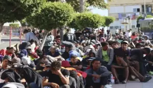 FOTOGRAFÍA. CEUTA (ESPAÑA), 25 DE AGOSTO DE 2026. Multitudes de inmigrantes ilegales marroquíes de la invasión de Ceuta del miércoles 29, jueves 30 y viernes 31 de julio de 2026, de los más de 80.000 invasores que no han querido retornar voluntariamente a Castillejos (Marruecos) como hicieron al menos 70.000 de ellos, aguardan este martes, 25 de agosto de 2026, en los alrededores para poder acceder al Centro de Acogida provisional habilitado por parte del Gobierno migracionista, globalista y socialcomunista en coalición entre Partido Socialista (PSOE) y Sumar -apoyado en extremistas y separatistas-, presidido por Pedro Sánchez Pérez-Castejón. Los españoles rechazan el traslado de estos invasores magrebíes, tanto de Menores Extranjeros No Acompañados (MENA) como los adultos, a la Península. También, desde la Península, el resto de compatriotas españolas rechazan los planes migracionistas del Gobierno de imposición de acogida en sus casas o en su Comunidad Autónoma. Y es que el próximo año 2027 es un año de elecciones locales, municipales y generales. Así que los socios del Gobierno y los partidos del Gobierno han optado guardar silencio sobre Ceuta. Efe