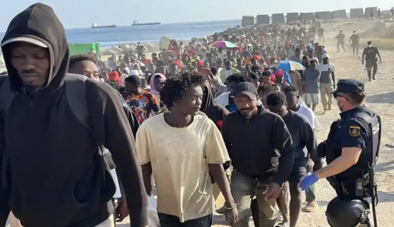 FOTOGRAFÍA. CEUTA (ESPAÑA), 20 DE AGOSTO DE 2026. Cerca de 1.700 migrantes han abandonado este jueves a pie y escoltados por la Policía Nacional la playa de El Trampolín, en el marco del dispositivo puesto en marcha para desalojar este asentamiento y trasladar a sus ocupantes a los nuevos recursos temporales de acogida habilitados en distintos puntos de Ceuta. Efe