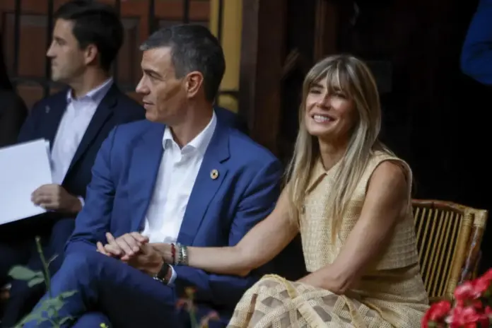 Giro en el caso Begoña juicio con jurado por tráfico de influencias y malversación FOTOGRAFÍA. SEVILLA (ESPAÑA), 30 DE JUNIO DE 2025. El presidente del Gobierno de España y secretario general del Partido Socialista, Pedro Sánchez, junto a su esposa, Begoña Gómez, durante la cena oficial en el Palacio de las Dueñas. En la imagen se aprecia un cercano gesto de complicidad, con ambos sentados y fuertemente entrelazados por las manos. Mientras Sánchez, vestido con un traje azul y camisa blanca sin corbata, mantiene una mirada atenta de perfil, Gómez, luciendo un vestido calado en tono beige de la diseñadora Teresa Helbig, dibuja una amplia sonrisa y dirige su mirada hacia el frente con actitud relajada. Efe