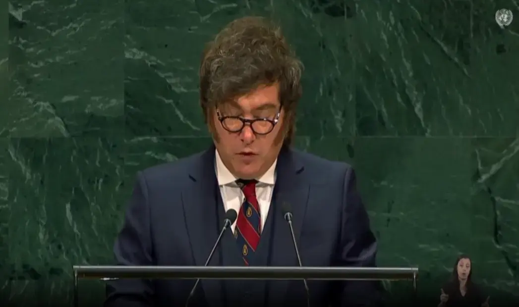 FOTOGRAFÍA. NACIONES UNIDAS, 23 DE SEPTIEMBRE DE 2026. El presidente de la República de Argentina, Javier Milei, lee atentamente sus notas durante su intervención en la tribuna oficial de la Asamblea General de las Naciones Unidas. Vestido con un traje oscuro, chaleco, camisa blanca y una corbata de rayas rojas y azules, el mandatario aparece flanqueado por dos micrófonos sobre el atril, recortado contra el característico fondo de mármol verde veteado del salón de plenos, con el emblema de la organización visible en la esquina superior derecha y la intérprete de lengua de signos en el recuadro inferior. Lasvocesdelpueblo (Ñ Pueblo).