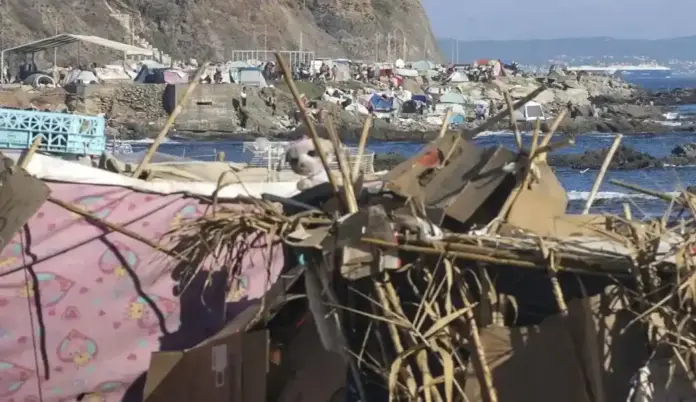 Presión extrema en Ceuta El Gobierno agiliza la filiación de inmigrantes irregulares que malviven en campamentos callejeros FOTOGRAFÍA. CEUTA, 26 DE SEPTIEMBRE DE 2026. Un extenso e improvisado campamento de chabolas levantado por miles de inmigrantes ilegales de origen marroquí y subsahariano abarrota por completo la zona rocosa y el litoral de la playa del Trampolín. En primer plano, se observa la precaria estructura de un habitáculo clandestino construido a base de cartones, maderas, cañas y plásticos de diversos colores, rematada con un peluche infantil como parte del entorno de asentamiento informal. Al fondo, a faldas de la ladera costera, se agolpan decenas de tiendas de campaña donde pernoctan los ciudadanos extranjeros en situación irregular, con presencia visible de personas moviéndose por los accesos y un buque mercante navegando al fondo en aguas del Estrecho. Esta ocupación de los espacios públicos refleja la grave crisis de seguridad y vecinal que sufre la ciudad autónoma, cumpliéndose hoy exactamente 58 días desde el inicio de la entrada masiva sin precedentes del pasado jueves 30 de julio de 2026. EFE