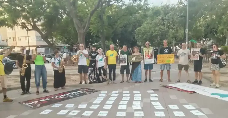 FOTOGRAFÍA. ALGEMESÍ (ESPAÑA), 20 DE SEPTIEMBRE DE 2026. Un grupo integrado por unas quince personas pertenecientes a la plataforma antitaurina se congrega en un espacio público empedrado de Algemesí durante la jornada de protesta de este domingo. Los manifestantes se disponen en fila portando pancartas y carteles informativos en los que se leen lemas como "No es cultura, es tortura" y "Subvenciones taurinas para educación pública, bomberos y sanidad". Algunos de los integrantes de la cabecera portan instrumentos musicales de viento-metal y de percusión. Frente a ellos, extendidas ordenadamente sobre el pavimento, se aprecian decenas de cartulinas de color blanco alineadas en hileras simétricas que recogen datos y mensajes explicativos dirigidos a los ciudadanos del municipio. Lasvocesdelpueblo (Ñ Pueblo)