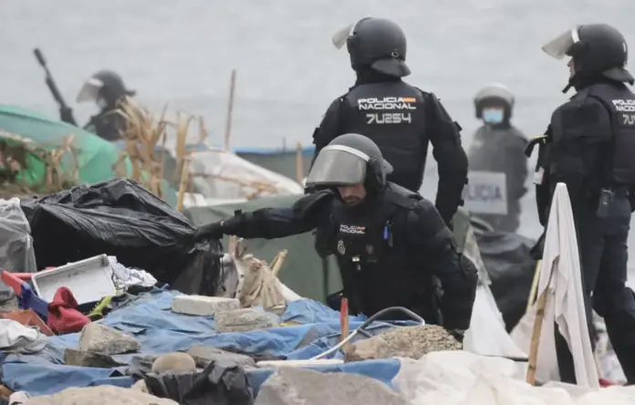 350 agentes asaltan la playa de El Trampolín en Ceuta para desalojar a los invasores marroquíes FOTOGRAFÍA. CEUTA, 04 DE OCTUBRE DE 2026. Efectivos de las Unidades de Intervención Policial (UIP) de la Policía Nacional registran y desmantelan los campamentos callejeros ilegales asentados en la playa de El Trampolín de Ceuta durante el macrooperativo desplegado este domingo para el desalojo forzoso de miles de inmigrantes ilegales marroquíes. En la imagen se observa a varios agentes provistos con equipamiento antidisturbios integral, cascos y escudos protectores, interviniendo entre las estructuras precarias, plásticos y acumulaciones de basura levantadas en el arenal ceutí tras 66 días de ocupación masiva e insalubridad pública. EFE