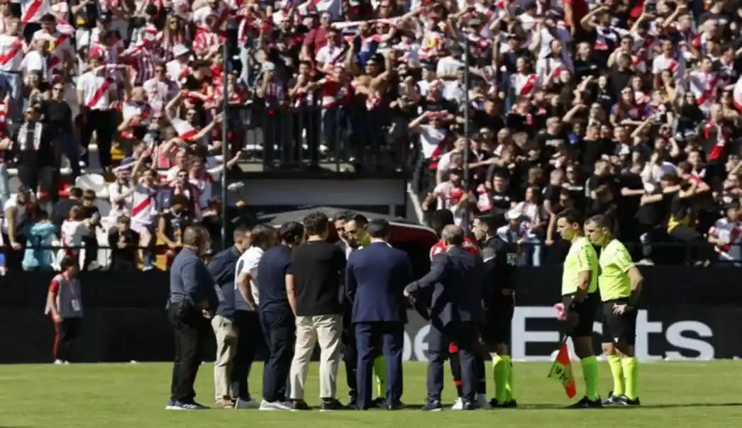 FOTOGRAFÍA. MADRID, 10 DE OCTUBRE DE 2026. El árbitro José María Sánchez Martínez (c) habla con miembros de ambos equipos antes de comunicar la suspensión definitiva del partido entre el Rayo Vallecano y el Athletic de Bilbao, después de que la afición rayista protestara contra la gestión de Martín Presa lanzando aviones de papel y bolas pequeñas de plástico, este sábado. EFE